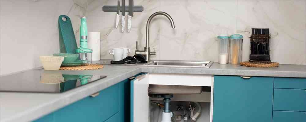 An image of a sink with an open cabinet showing piping beneath the sink for the blog article what not to put down a sink drain